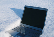 Das Bild zeigt einen Laptop, der im tiefen Schnee liegt