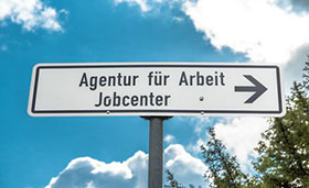 Wegweiser mit der Aufschrift "Jobcenter" und "Agentur fr Arbeit"