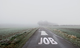 Eine Strae in einer vernebelten Landschaft, darauf die weie Aufschrift "JOB" und ein Richtungspfeil zum Horizont