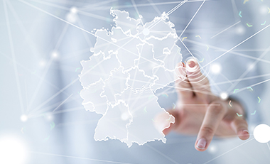 Hand vor einer transparenten Struktur mit Deutschlandkarte, Finger zeigt auf eine Stelle der Karte
