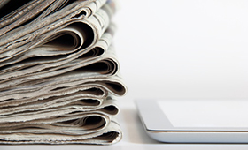 Zeitungsstapel neben Tablet