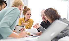 Arbeitsatmosphäre: Mehrere Personen diskutieren an einem Tisch Arbeitsatmosphäre: Mehrere Personen diskutieren an einem Tisch