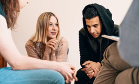 Drei Personen im Gesprch, an einem Tisch sitzend
