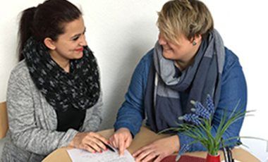 Eine jüngere und eine ältere Frau im Gespräch an einem kleinen Tisch. Eine jüngere und eine ältere Frau im Gespräch an einem kleinen Tisch.
