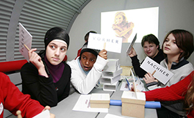 Im "Zeittunnel": Schülerinnen und Schüler sitzen an einem langen Tisch und halten Pappschilder mit "Vorher"- oder "Nachher"-Aufdruck hoch Im "Zeittunnel": Schülerinnen und Schüler sitzen an einem langen Tisch und halten Pappschilder mit "Vorher"- oder "Nachher"-Aufdruck hoch