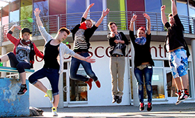 Mehrere Jugendliche springen vor dem Gebäude des Don-Bosco-Zentrums hoch