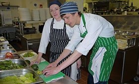 Ein Praktikant und eine Praktikantin arbeiten in einer Großküche