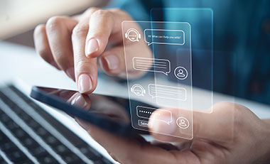 Eine Hand h�lt ein Smartphone, die andere tippt. Eingespiegelt eine Chatbot-Konversation.