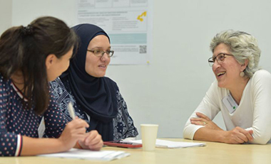Drei Frauen sitzen an einem Tisch und unterhalten sich