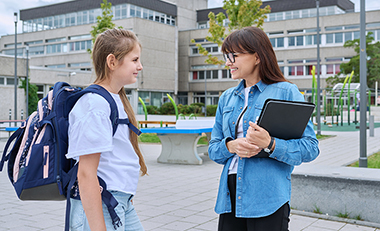 Eine Schülerin und eine Lehrerin im Gespräch auf dem Schulhof Eine Schülerin und eine Lehrerin im Gespräch auf dem Schulhof