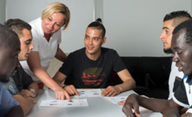 Junge Migrantinnen und Migranten mit einer Lehrerin im Sprachkurs. Junge Migrantinnen und Migranten mit einer Lehrerin im Sprachkurs.