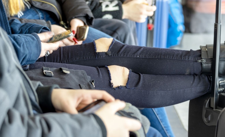 Auf einer Bank sitzen junge Menschen, von denen nur Beine und Hände zu sehen sind. Alle halten ein Handy. Auf einer Bank sitzen junge Menschen, von denen nur Beine und Hände zu sehen sind. Alle halten ein Handy.