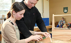 In der Holzwerkstatt arbeiten ein junger Mann und eine junge Frau an einer Werkbank. Bild: Vesbe e.V.