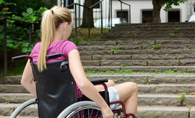 Frau im Rollstuhl vor Treppe als Hindernis Frau im Rollstuhl vor Treppe als Hindernis