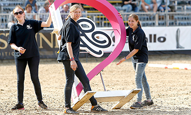 Junge Frauen tragen ein Gestell ins Reitstadion