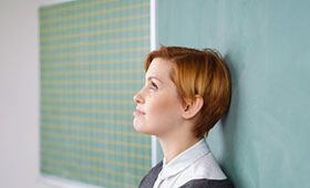 Lehrerin, mit dem Rcken an der Tafel lehnend