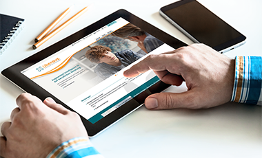Ein Tablet, auf dem die Webseite von �beraus zu sehen ist, wird mit der Hand bedient.