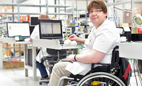Rollstuhlfahrer am Arbeitsplatz in einer Fabrik