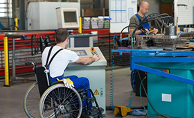 Mitarbeiter mit Rollstuhl in einem Produktionsbetrieb