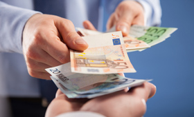 Eine Hand legt Geldscheine auf eine andere