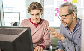 Junge und Mann sitzen gemeinsam vor dem Computer