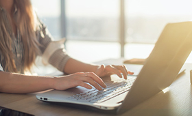 junge Frau sitzt am Laptop und tippt