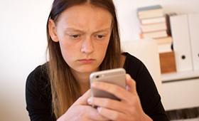 Teenager blickt kritisch auf Smartphone