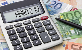 Taschenrechner, der auf dem Display "Hartz IV" anzeigt, und Geldscheine