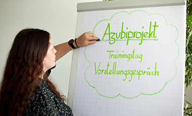 Auszubildende schreibt auf ein Flipchart Auszubildende schreibt auf ein Flipchart