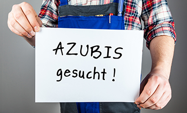 Brustbild eines Mannes im "Blaumann", der ein Schild mit der Aufschrift "Azubis gesucht" in den Händen hält Brustbild eines Mannes im "Blaumann", der ein Schild mit der Aufschrift "Azubis gesucht" in den Händen hält