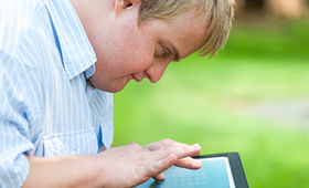 Junger Mann mit Down-Syndrom arbeitet mit Laptop