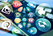 App-Symbole vor dem Hintergrund eines unscharf gestellten Smartphones und einer Tastatur