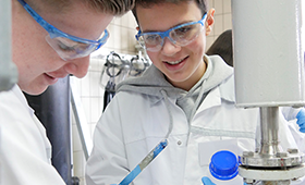 Zwei Junge Teilnehmer des Berufsorientierungsprogramms mit Schutzbrillen in einem Labor