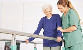 Junge Altenpflegerin hält Seniorin am Arm