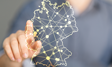 Finger zeigt auf digitale Deutschlandkarte, in der einige Punkte markiert sind