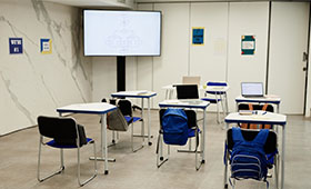 Blick in ein Klassenzimmer mit Whiteboard und Laptop auf einem Tisch.