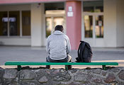 Sicht von hinten auf Mann und Rucksack auf einer Sitzbank