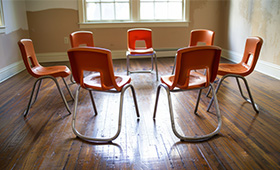 Raum mit Stuhlkreis aus orangefarbenen Sthlen auf Parkettboden