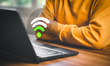 Laptop mit darüberliegender Grafik eines schwachen WLAN-Signals und sitzende Person mit verschränkten Armen Laptop mit darüberliegender Grafik eines schwachen WLAN-Signals und sitzende Person mit verschränkten Armen
