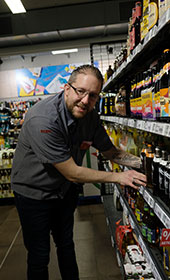 Ein junger Mann r�umt ein Supermarktregal ein