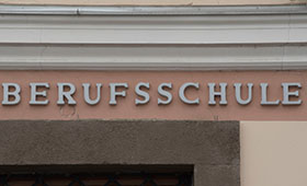An einer Hausfassade, ber der Eingangstr, sieht man das Wort Berufsschule.  Bild: Adobe Stock | elmar gubisch