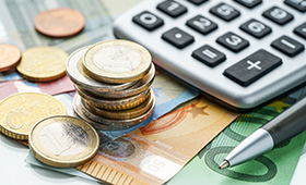Euro-Geldscheine und Mnzen, daneben ein Taschenrechner und ein Kugelschreiber