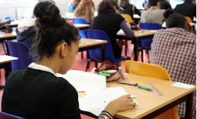 Eine Schlerin arbeitet im Klassenraum  an ihren Materialien.