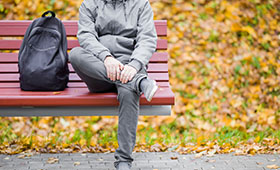 Auf einer Parkbank im Herbst sitzt allein ein Junge. Sein Gesicht ist nicht zu sehen.  Bild: fotoduets | Adobe Stock