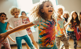 Eine Gruppe von tanzenden Kindern, im Vordergrund ein lachendes Mdchen