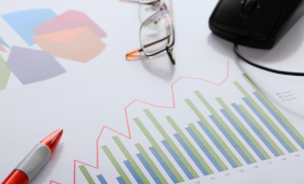 Bild mit Auswertungsgrafiken, einer Brille, Kugelschreiber und Maus