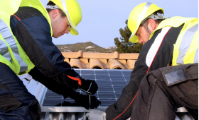 Zwei Elektroinstallateure installieren eine Solaranlage auf einem Dach