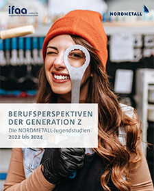 Eine junge Frau schaut mit einem Auge durch das Loch eines Schraubenschl�ssels, im Hintergrund ist eine Industriehalle zu sehen.
