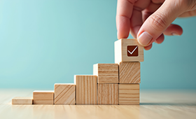 Aus Holzw�rfeln gebildete Treppe, eine Hand legt einen W�rfel hinzu