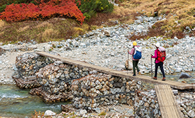 Zwei Frauen mit Wanderausrüstung überqueren eine improvisierte Brücke im Gebirge. Zwei Frauen mit Wanderausrüstung überqueren eine improvisierte Brücke im Gebirge.